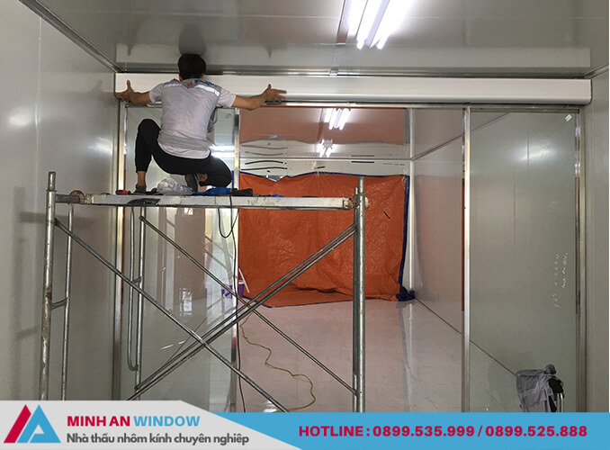 Nhân viên của Minh An Window đang lắp đặt mặt ốp inox cho cửa kính tự động Woosung cho nhà xưởng